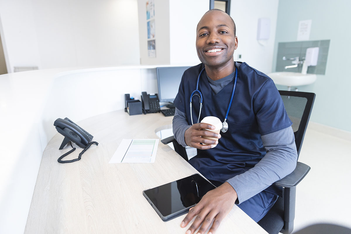 A smiling doctor at Susan Baker MD's office greets patients at the front desk